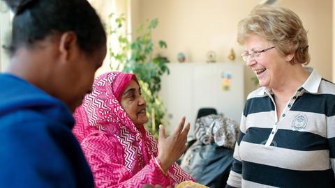 Drei Frauen verschiedener Herkunft und Kleidung sprechen miteinander. 