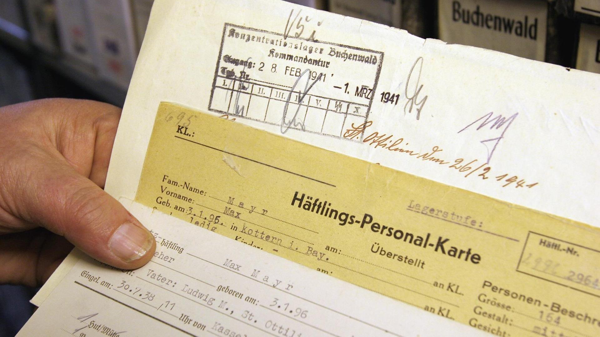Eine Hand hält in den Räumen des Internationalen Suchdienstes des Roten Kreuzes (ITS) im nordhessischen Bad Arolsen Häftlingskarten und weitere Dokumente eines Zwangsarbeiters (Archivbild vom 25.11.2004). Um die oft erschütternden Dokumente für die kommenden Generationen zu erhalten, hat die Restaurierung der vom Verfall bedrohten Akten begonnen. Der ITS verwaltet 47 Millionen Dokumente mit Hinweisen auf 17 Millionen Opfer des NS-Regimes. Jährlich sollen in einer Spezialmaschine rund 200 000 Dokumente entsäuert und entlaminiert werden, sagt ITS-Archivverwalter Udo Joos. Foto: Uwe Zucchi dpa/lhe (zu lhe Korr-Bericht "Kriegspapier zerfällt: Zwangsarbeiter-Archiv wird restauriert" vom 13.12.) +++(c) dpa - Report+++