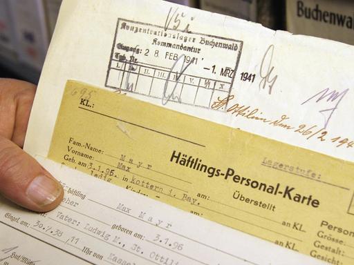 Eine Hand hält in den Räumen des Internationalen Suchdienstes des Roten Kreuzes (ITS) im nordhessischen Bad Arolsen Häftlingskarten und weitere Dokumente eines Zwangsarbeiters (Archivbild vom 25.11.2004). Um die oft erschütternden Dokumente für die kommenden Generationen zu erhalten, hat die Restaurierung der vom Verfall bedrohten Akten begonnen. Der ITS verwaltet 47 Millionen Dokumente mit Hinweisen auf 17 Millionen Opfer des NS-Regimes. Jährlich sollen in einer Spezialmaschine rund 200 000 Dokumente entsäuert und entlaminiert werden, sagt ITS-Archivverwalter Udo Joos. Foto: Uwe Zucchi dpa/lhe (zu lhe Korr-Bericht "Kriegspapier zerfällt: Zwangsarbeiter-Archiv wird restauriert" vom 13.12.) +++(c) dpa - Report+++