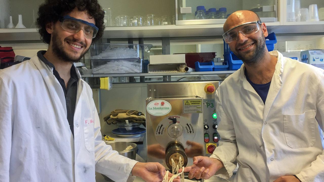 Francesco Brandi und Majd Al-Naji stehen neben einer Nudelmaschine.
