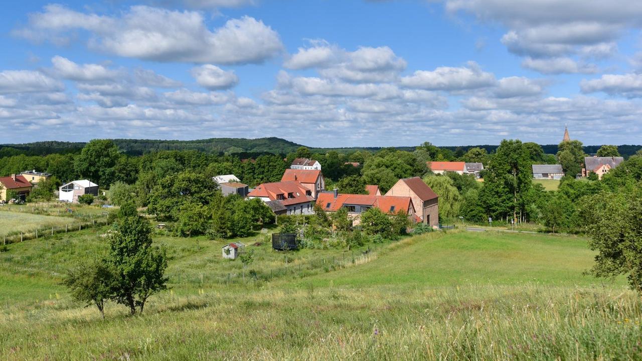 Blick auf das Ökodorf Brodowin im Landkreis Barnim, im Vordergrund eine Wiese darüber blauer Himmel.