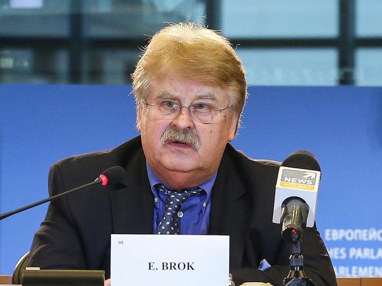Elmar Brok sitzt an einem Tisch und spricht in ein Mikrofon