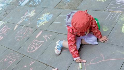 Ein Kind malt in Hamburg mit Kreide auf dem Fußweg. 