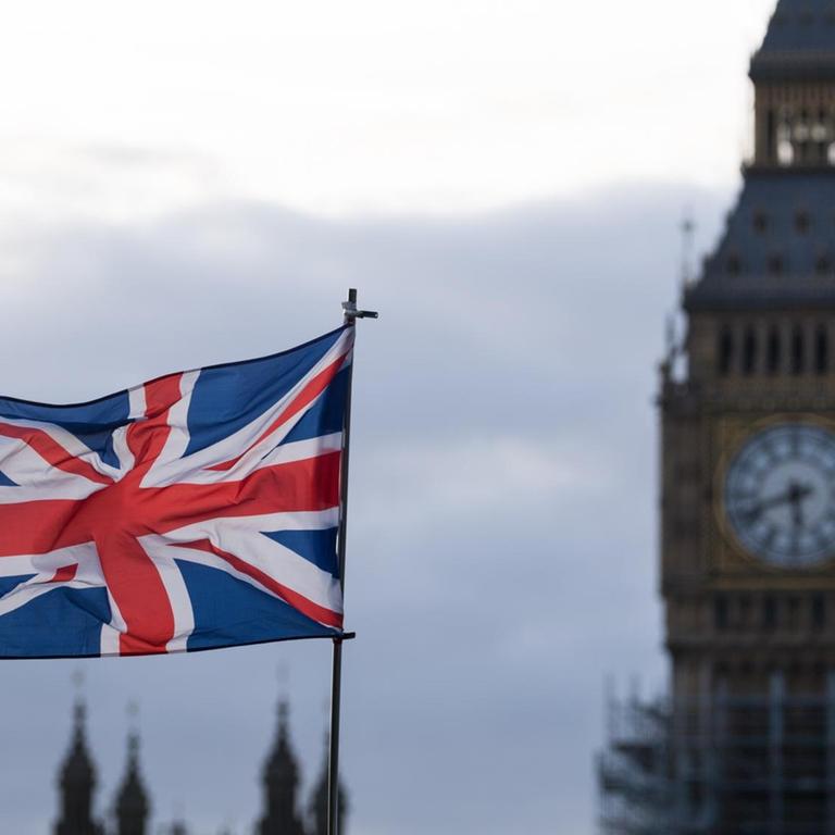 Eine Fahne vom Vereinigtem Königreich (Union Jack) weht am  in London (Großbritannien) im Wind. Im Hintergrund ist der Uhrturm Elizabeth Tower mit dem Big Ben zu sehen.