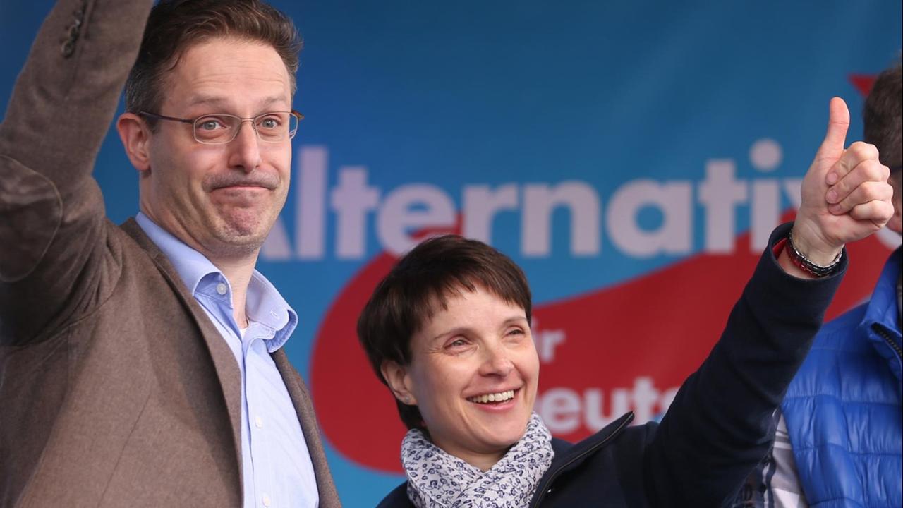 Pretzell und Petry stehen nebeneinander auf der Bühne und recken ihre Daumen in die Höhe.