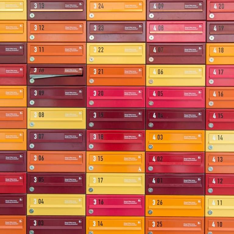 Sie sehen farbige Briefkästen eines Studentenwohnheimes in München.