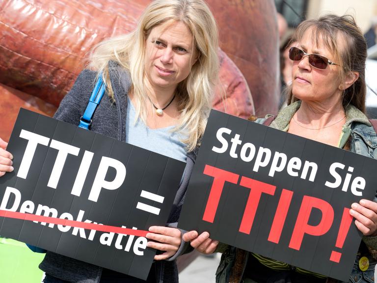 Zwei Frauen protestieren am 06.05.2014 vor dem Brandenburger Tor in Berlin gegen das Freihandelsabkommen TTIP zwischen der EU und den USA mit Transparenten.