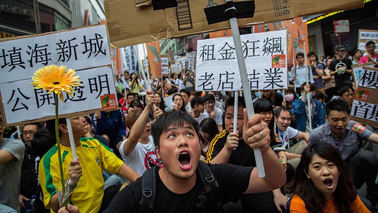 Protestierende rufen Slogans und halten Plakate hoch bei einer Demonstration gegen Job-Kürzungen und schlechte Lebensbedingungen am 1. Mai 2014 in Macau. 