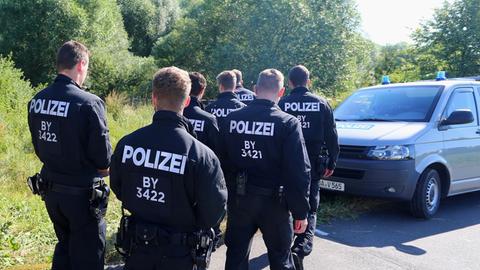 Polizisten durchsuchen am 19.07.2016 neben einem Weg bei Würzburg (Bayern) das Gelände nach Spuren. Am Montagabend war ein 17 Jahre alter Afghane mit einer Axt und einem Messer auf Fahrgäste in einem Regionalzug bei Würzburg-Heidingsfeld losgegangen.
