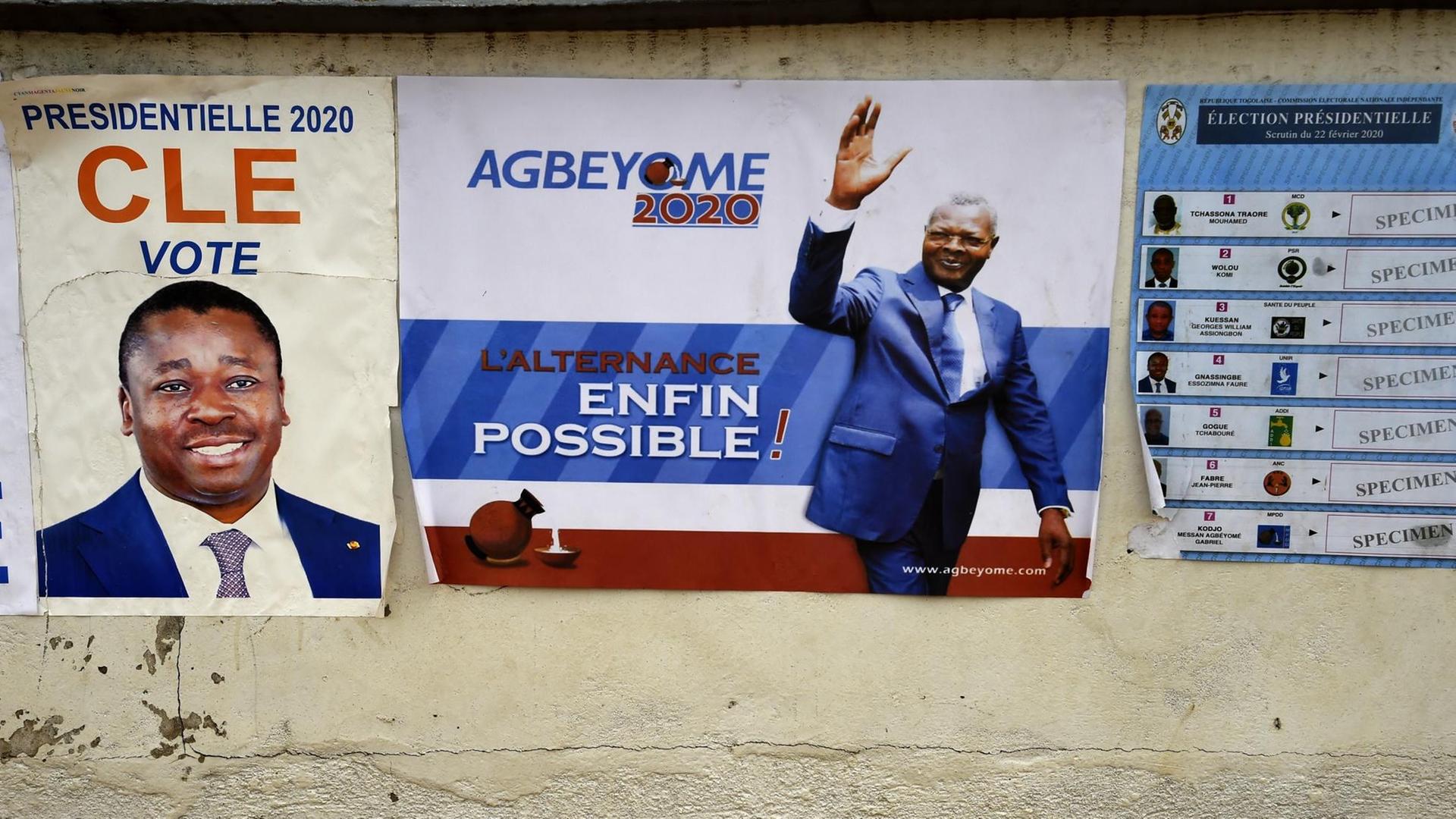 Auf an einer Wand hängenden Plakaten sind Kandidaten und Wahllisten abgebildet.