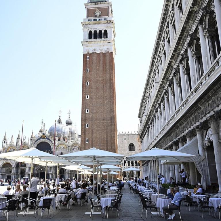 Am 27. Juni 2020 wurden auf dem Markusplatz in Venedig, Italien, die ersten Schirme aufgespannt, die den Platz vor dem Lokal abdecken werden, das vergrößert wurde, um die sichere Anordnung der Tische gemäß den Sicherheitsvorschriften zum Coronavirus zu ermöglichen. Die ersten Decken wurden vor dem Caffè Florian aufgestellt.