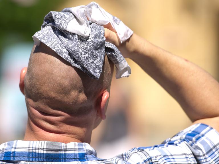 Ein Mann wischt sich mit einem Stofftuch über den Kopf