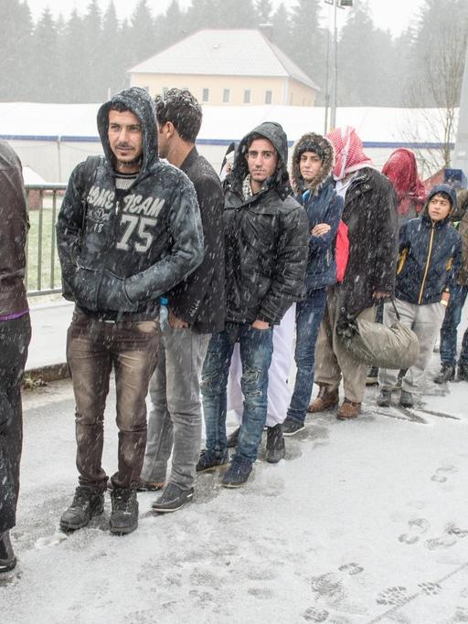 Flüchtlinge warten am 21.11.2015 an der deutsch-österreichischen Grenze nahe Wegscheid (Bayern) während eines Schneeschauers auf ihre Einreise nach Deutschland.