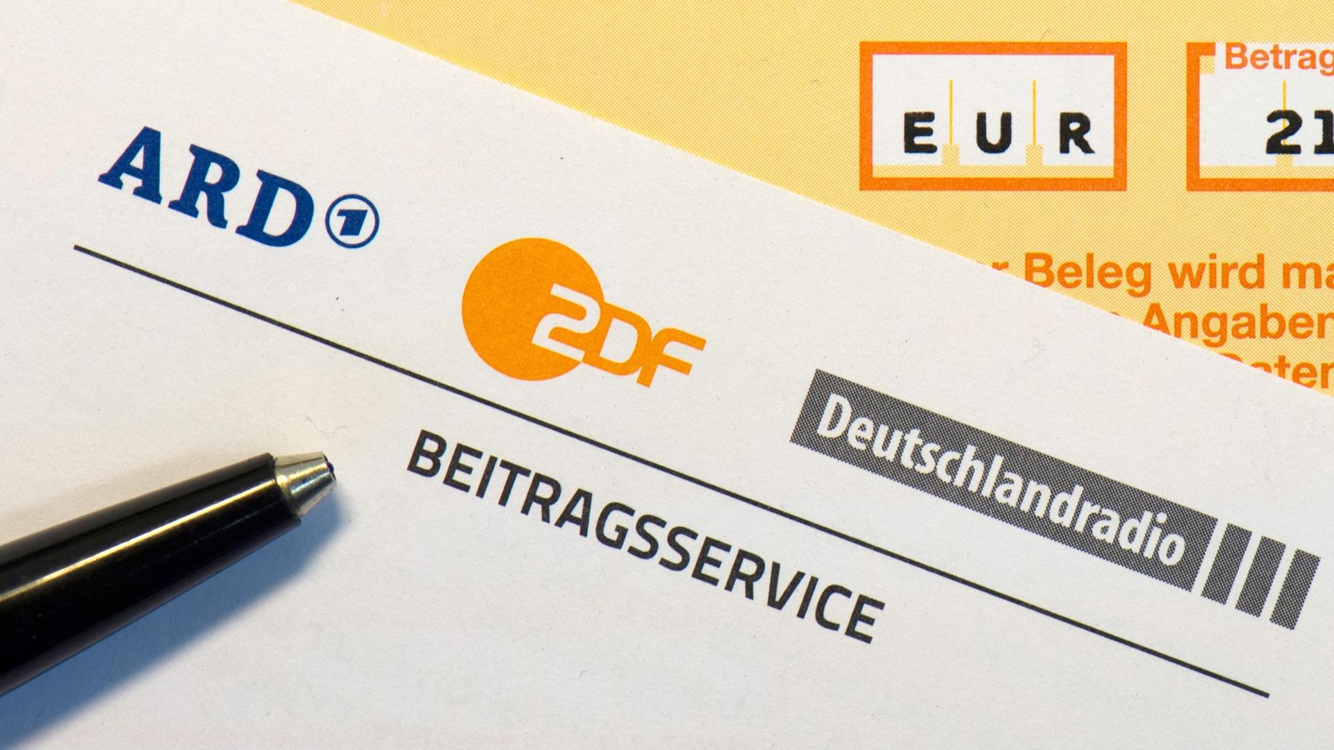 Auf einem Tisch liegt ein Überweisungsschein für den Beitragsservice von ARD, ZDF und Deutschlandradio.
