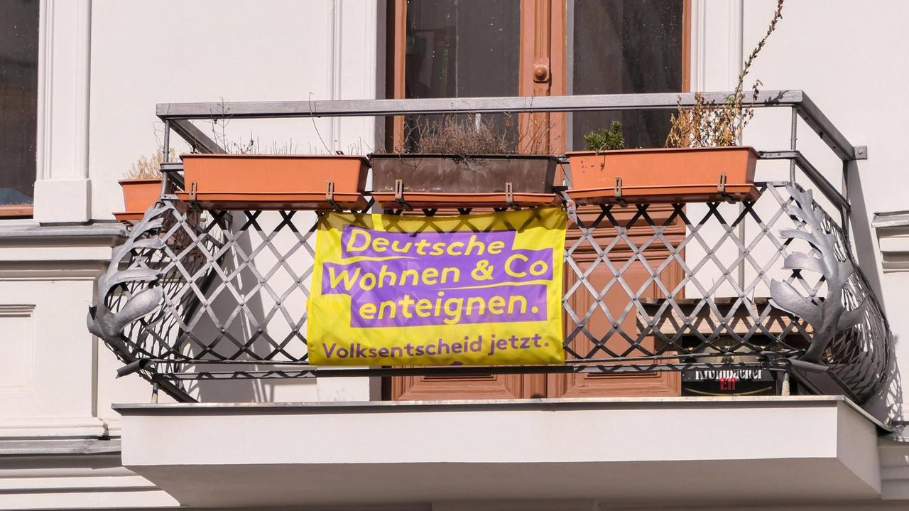 An einem Balkon eines Altbaus hängt ein Transparent, auf dem steht: Deutsche Wohnen und Co enteignen