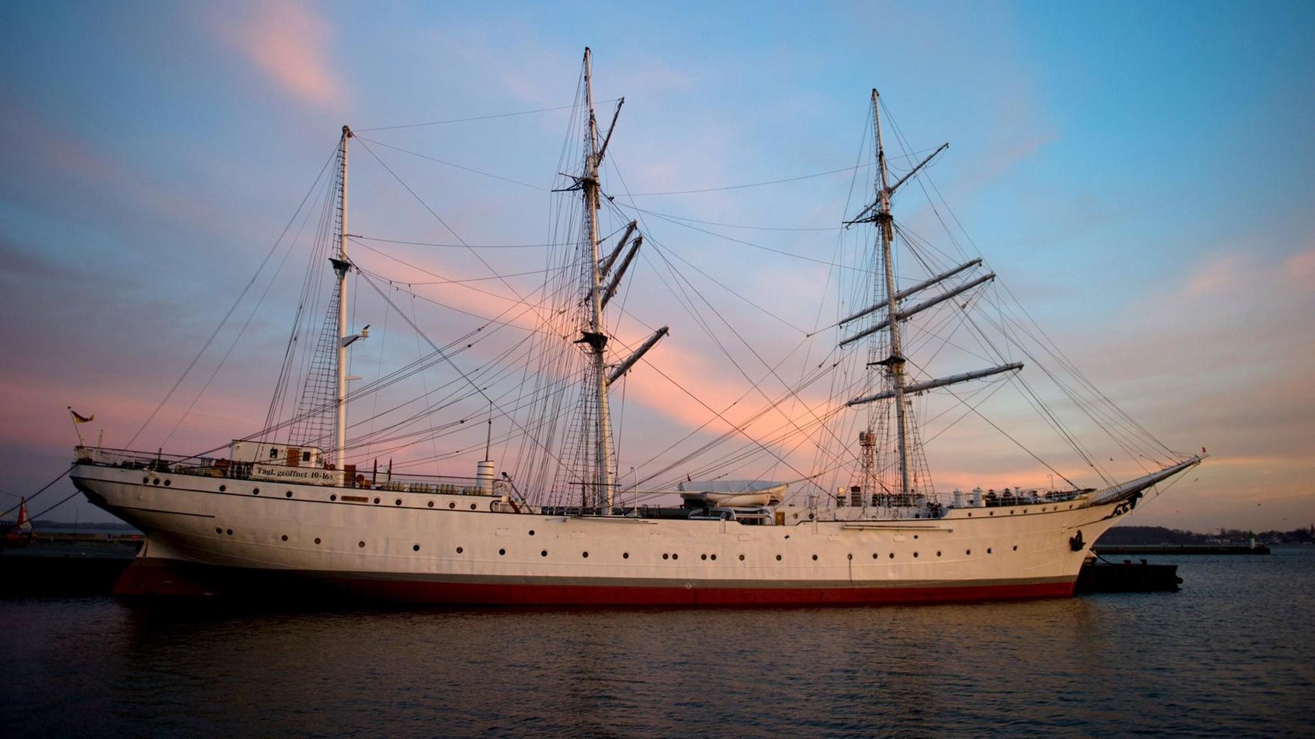 Die aufgehende Sonne taucht am 10.12.2015 den Himmel im Hafen von Stralsund (Mecklenburg-Vorpommern)