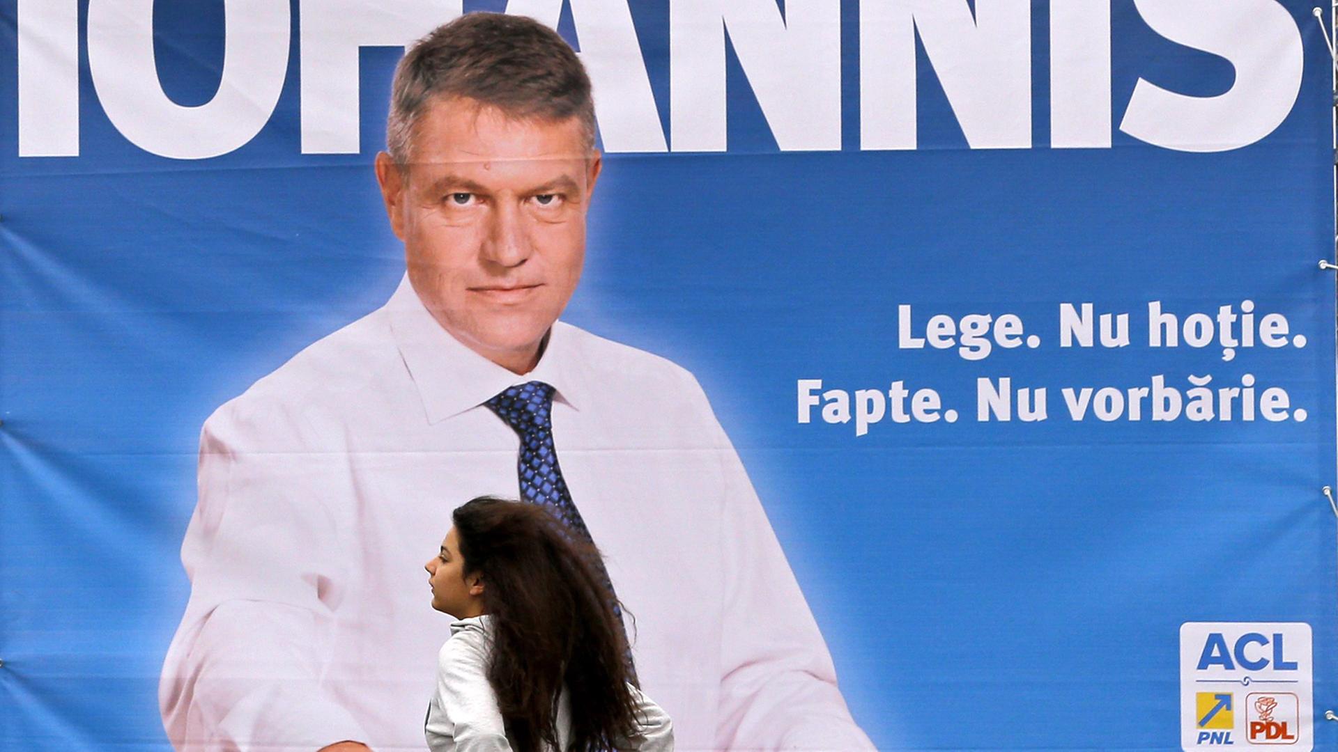 Eine Frau geht an einem Wahlplakat eines Kandidaten für die rumänische Präsientschaftswahl, Klaus Johannis, vorbei.