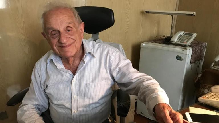 Der 90-jährige Albert Arie sitzt an seinem Schreibtisch.