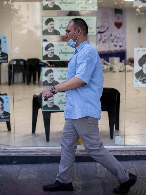Passant in Teheran vor Wahlplakaten für die Präsidentschaftswahl 2021 im Iran