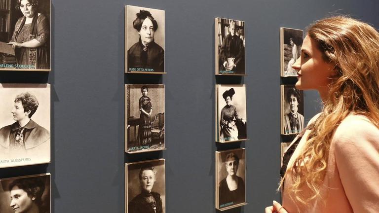 Eine Frau betrachtet historische Bildtafeln mit Portraits und Namen von Aktivistinnen der Frauenbewegung im Historischen Museum Frankfurt am Main.