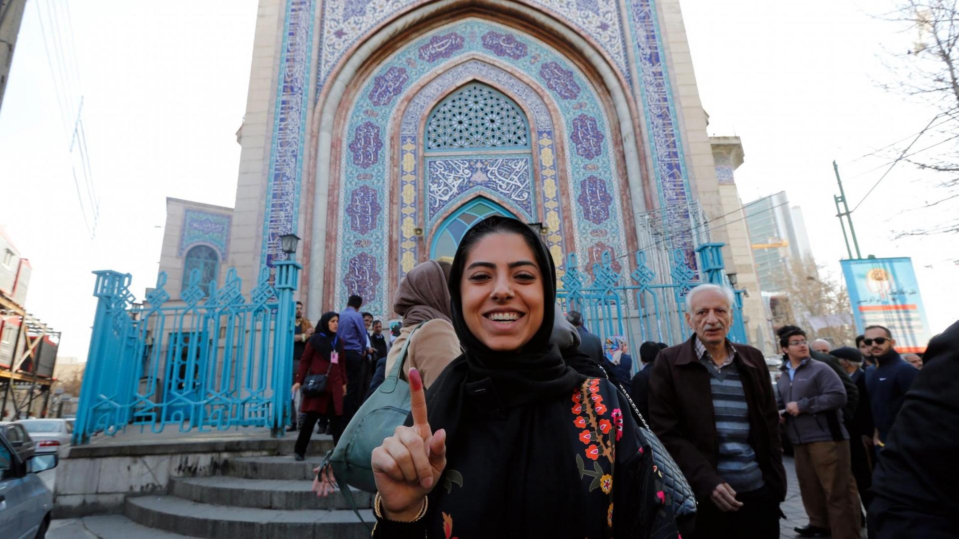 Eine junge Iranerin zeigt lächelnd ihren markierten Zeigefinger, nachdem sie ihre Stimme bei der Parlamentswahl in Teheran abgegeben hat.