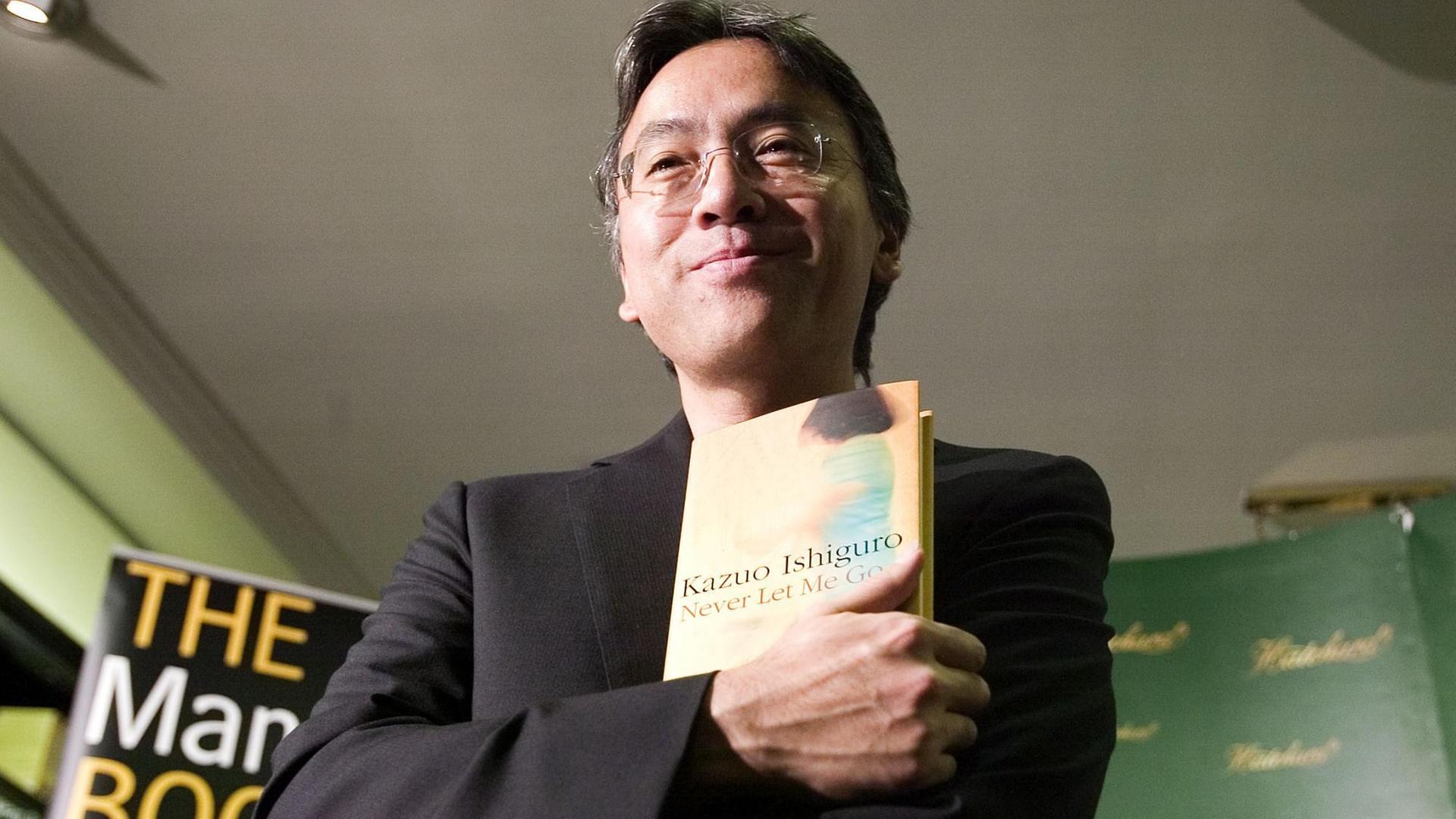 Der britisch-japanische Schriftsteller Kazuo Ishiguro hält eines seiner Bücher in der Hand.