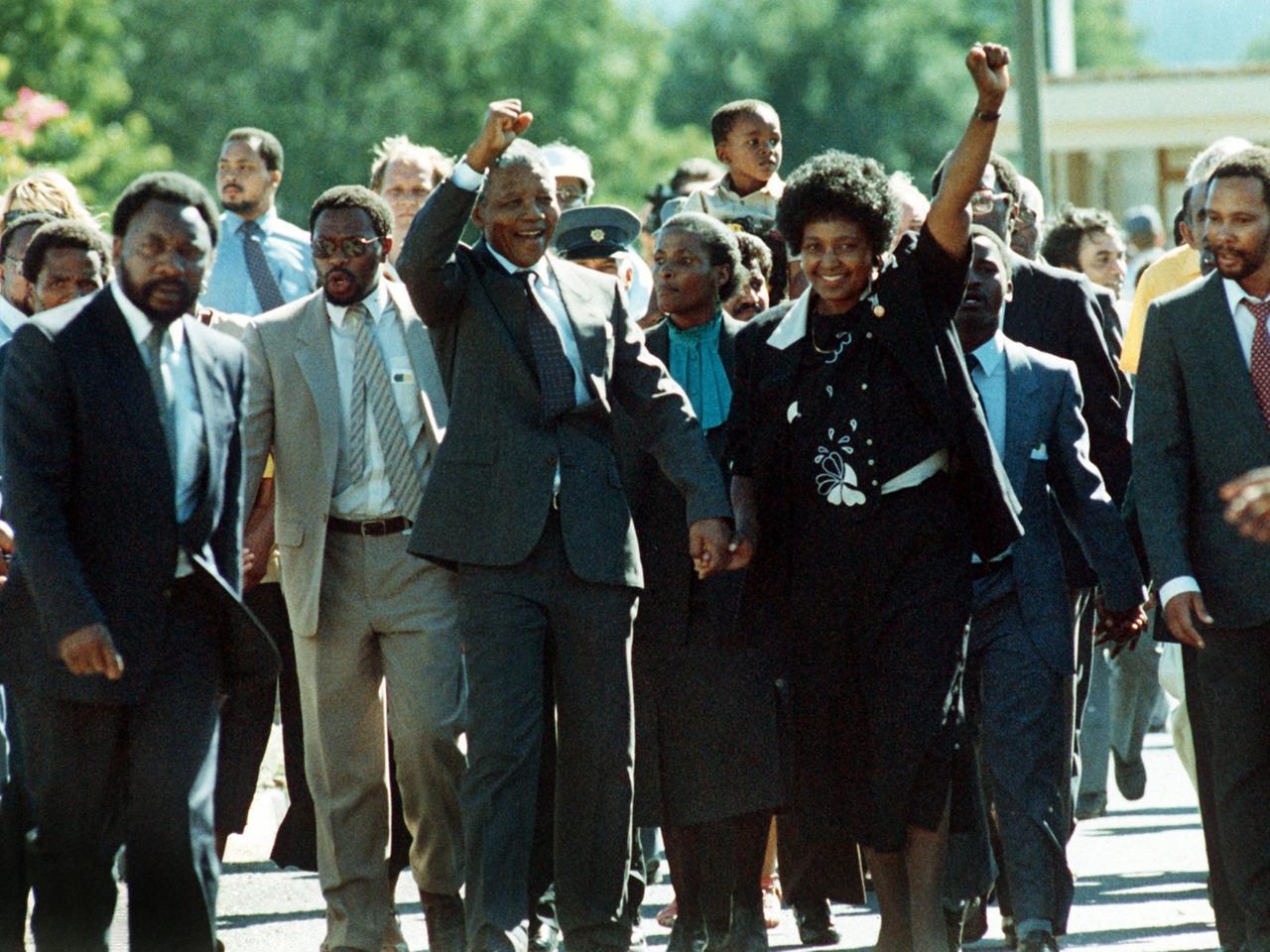 Nelson Mandela reckt, umringt von Unterstützern, seine Faust in die Luft.