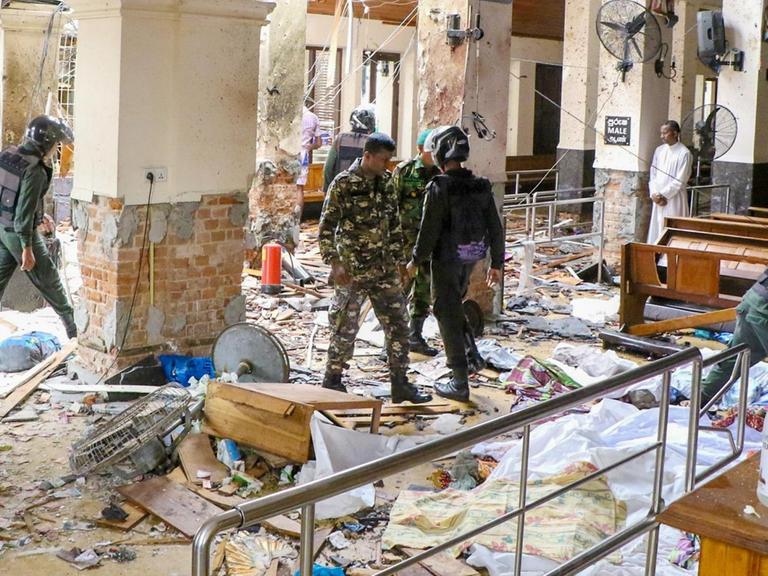 Die St. Antonius Kirche in Colombo ist nach einer Explosion verwüstet, Sicherheitskräfte gehen durch Trümmer