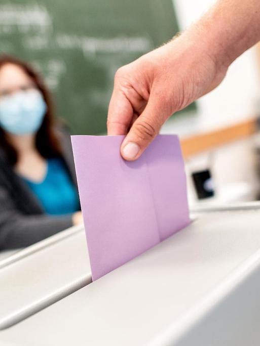Ein Wähler wirft in einem Wahllokal, das im Klassenraum einer Schule untergebracht ist, seinen Stimmzettel in die Wahlurne.