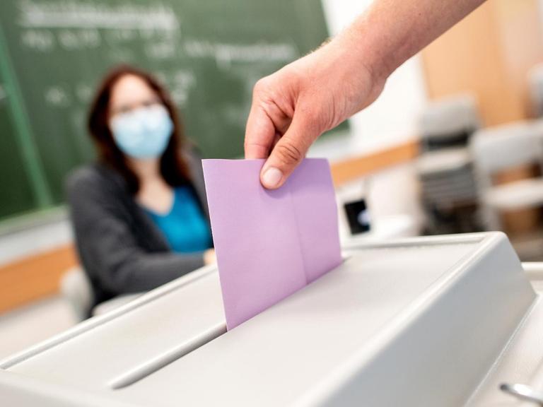 Ein Wähler wirft in einem Wahllokal, das im Klassenraum einer Schule untergebracht ist, seinen Stimmzettel in die Wahlurne.