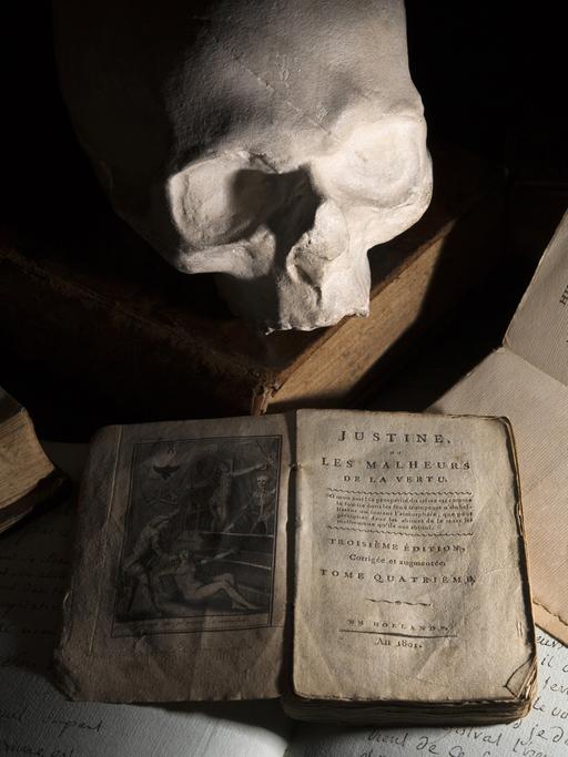 Ein Gipsabdruck des Totenschädels des Marquis de Sade ist neben älteren Ausgaben der Werke "Justine" (1801), "Juliette" (1797) und "L'union des arts ou les ruses de l'amour" (1810) zu sehen.