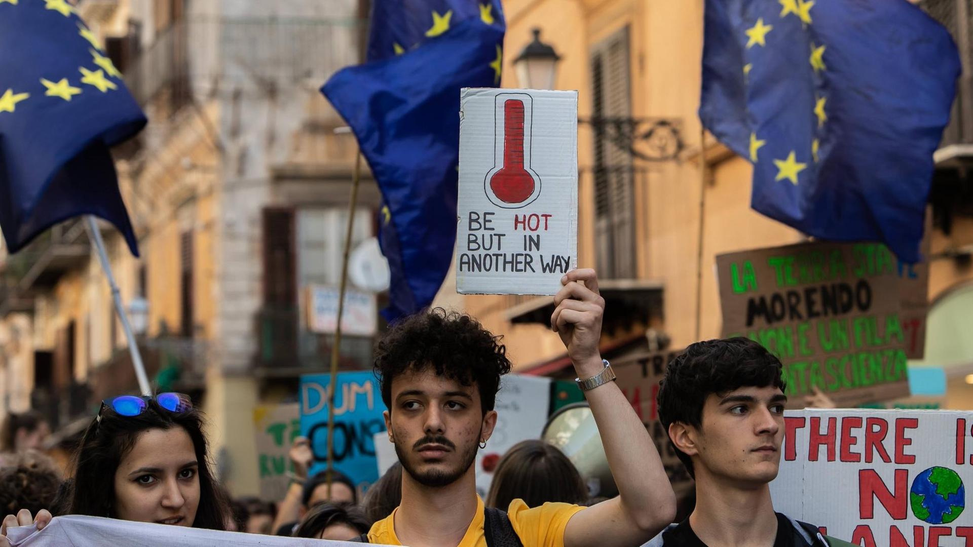 Junge Demonstranten bei Fridays for Future in der italienischen Stadt Palermo. Sie tragen Plakate gegen den Klimawandel und Europafahnen.