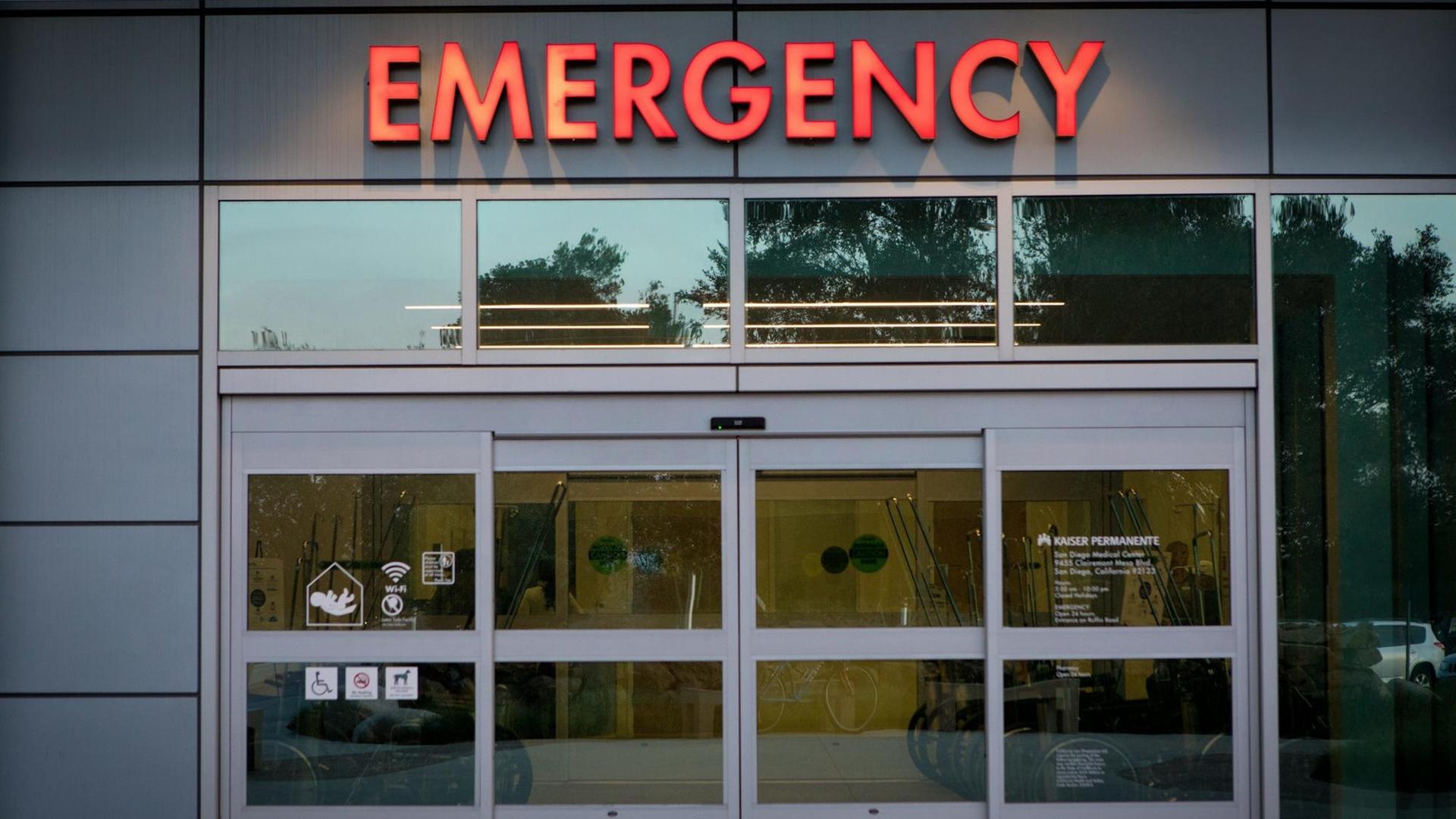 Blick auf ein breites Tor mit der Neon-Aufschrift "Emergency". Blick auf ein breites Tor mit der Neon-Aufschrift "Emergency".