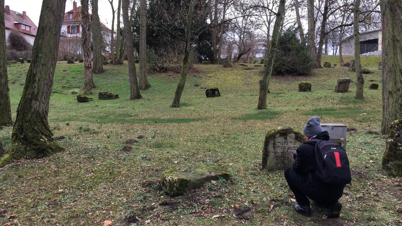 Ein Mann fotografiert einen Grabstein auf dem jüdischen Friedhof in Mainz.