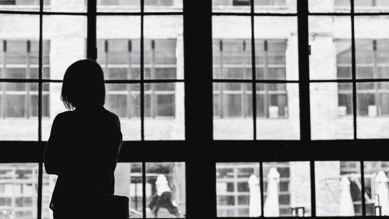 Eine Frau schaut aus ihrer Wohnung auf die gegenüberliegende Häiuserzeile