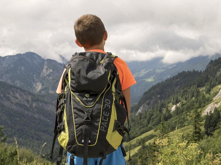 Ein junger Bergsteiger mit Rucksack blickt ins Kaisertal.