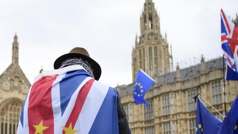 Ein Brexit-Gegner steht in die britische und die EU-Flagge gehüllt vor dem Parlamentsgebäude in London.