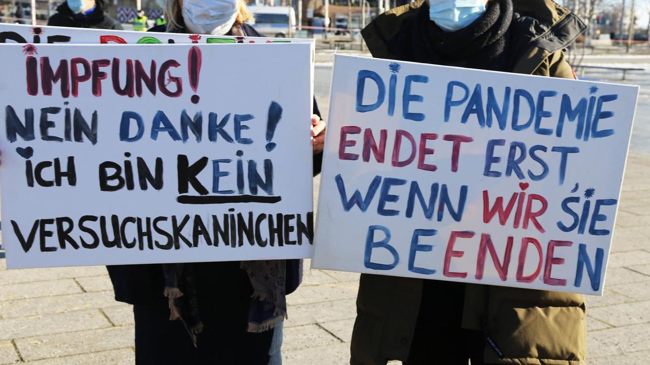 Zwei Personen halten Plakate mit der Aufschrift: Impfung - nein Danke! Ich bin kein Versuchskaninchen." und "Die Pandemie endet erst, wenn wir sie beenden." Demonstration gegen die Coronamaßnahmen in Mannheim. 