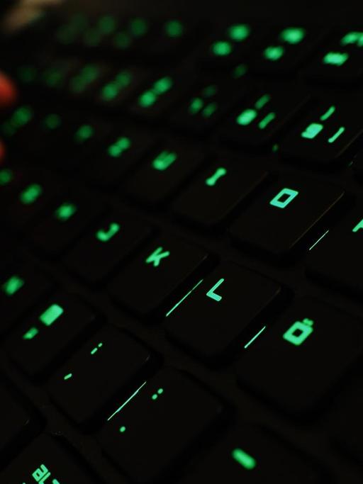 Ein Mann tippt auf einer beleuchteten Tastatur.