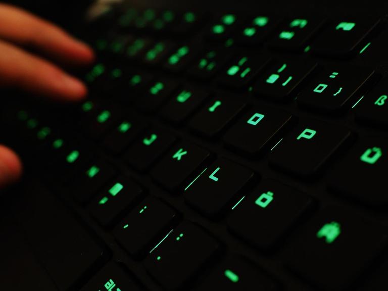 Ein Mann tippt auf einer beleuchteten Tastatur.