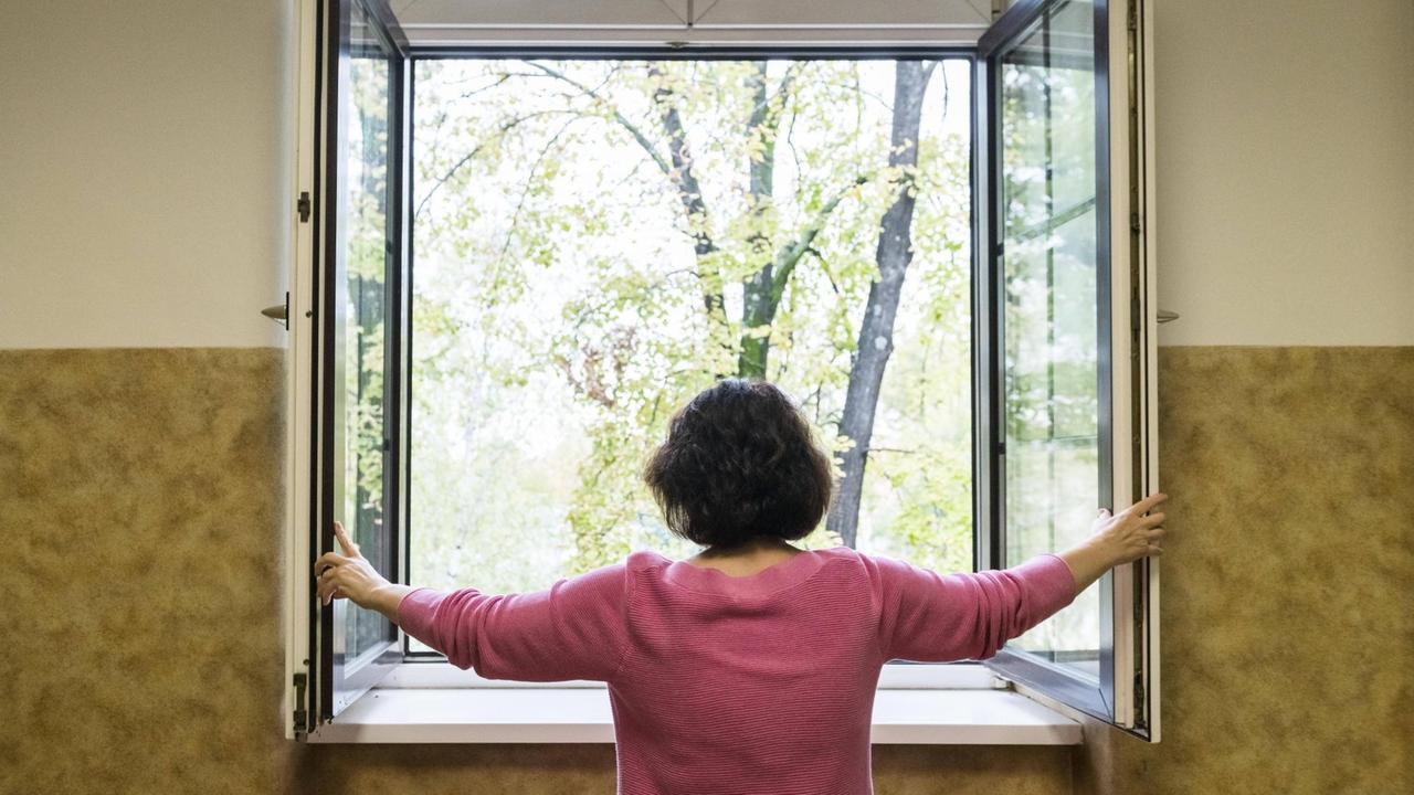 Eine Frau öffnet ein Fenster