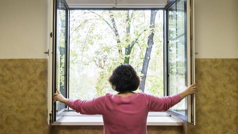 Eine Frau öffnet ein Fenster