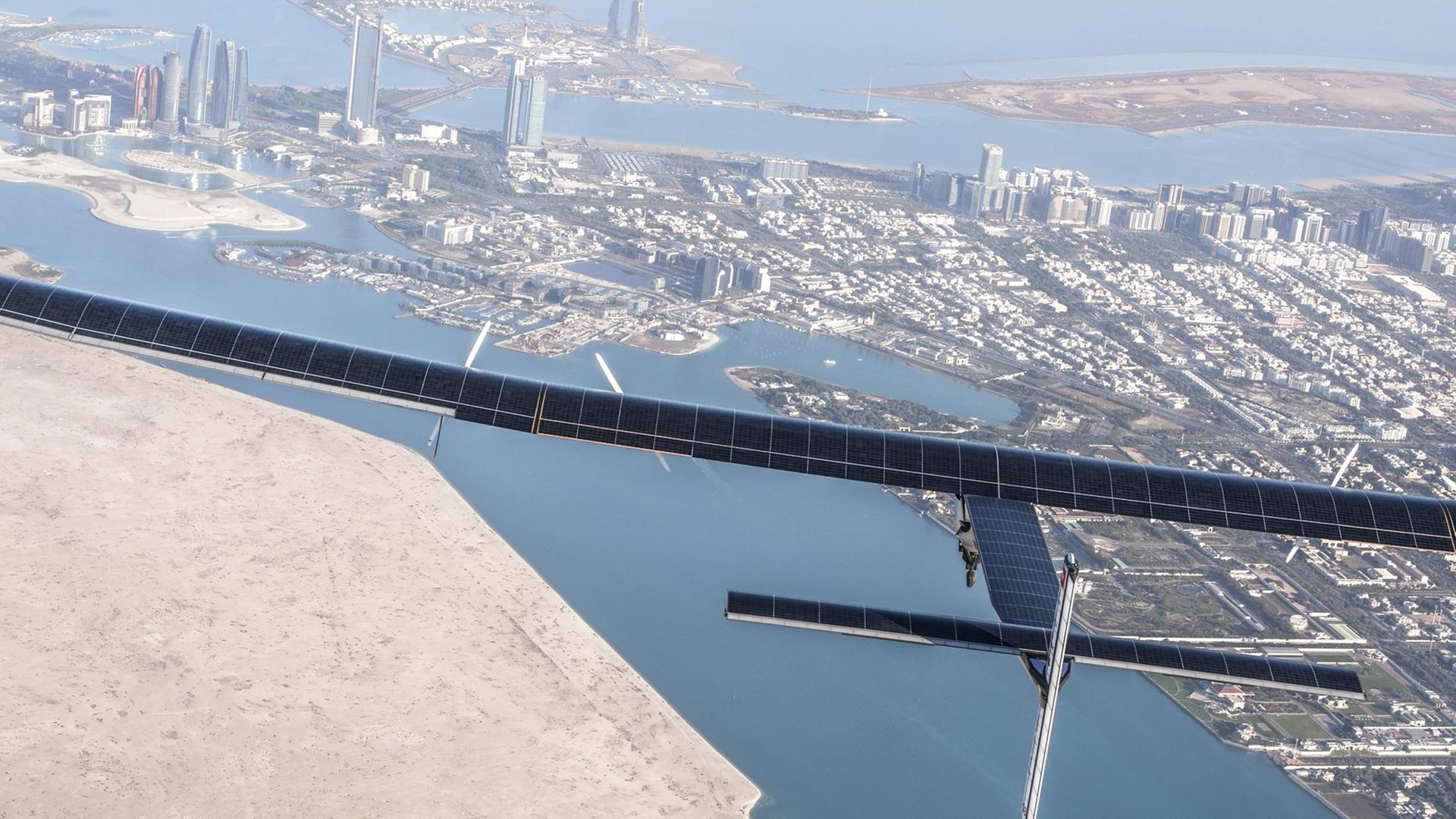 Das schmale Flugzeug mit langen Flügeln fliegt über die Stadt Abu Dhabi.
