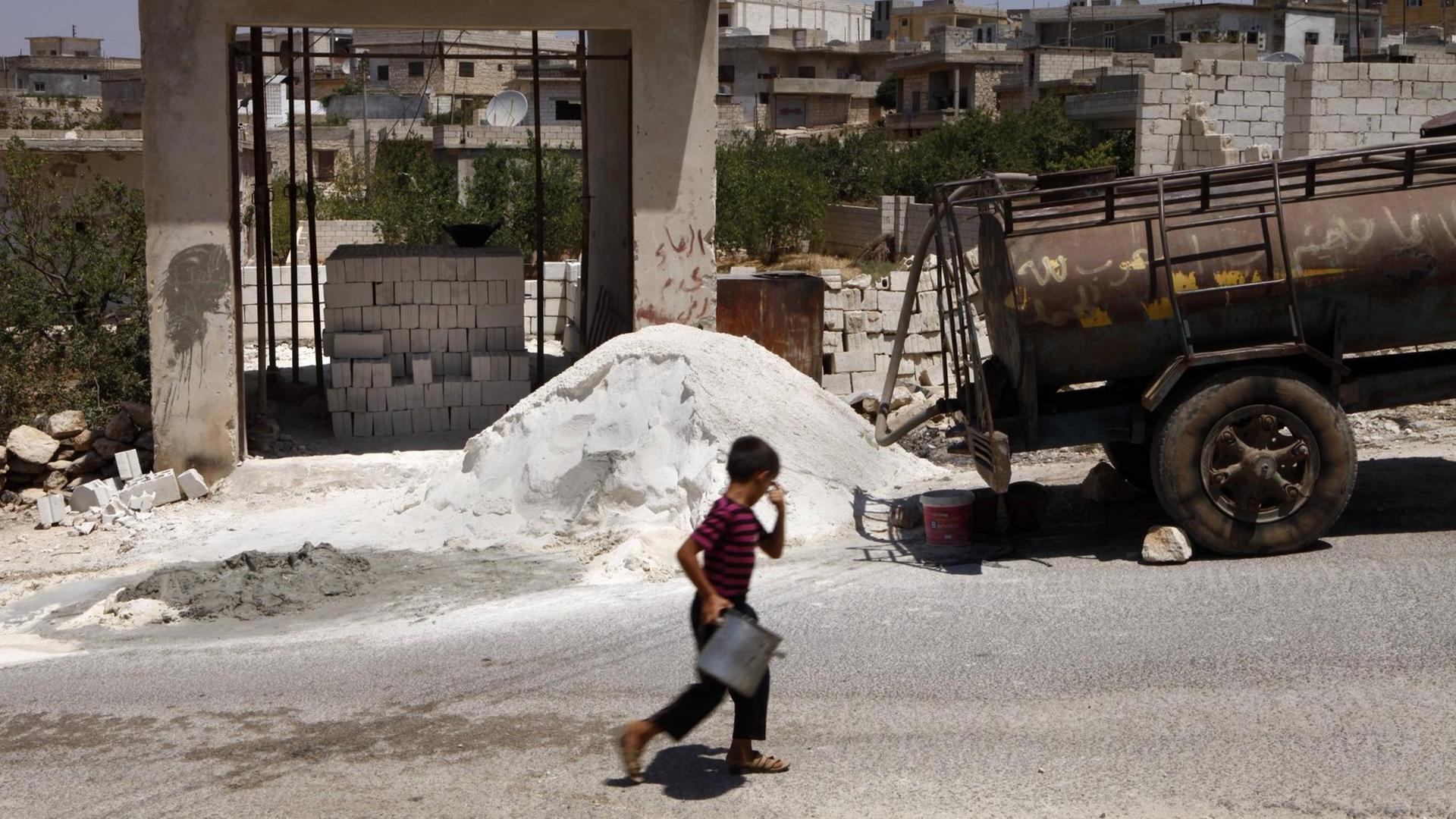 Ein Junge läuft vor eine Baustelle entlang in der Provinz Idlib, Syrien.
