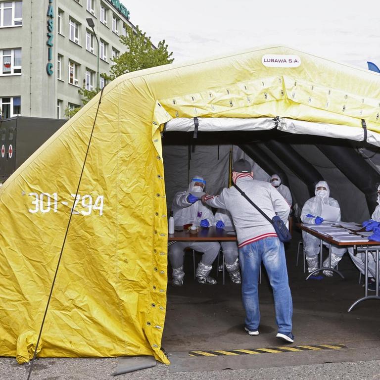 Bergleute in Katowice werden in einem gelben Zelt auf das Corona-Virus getestet.

