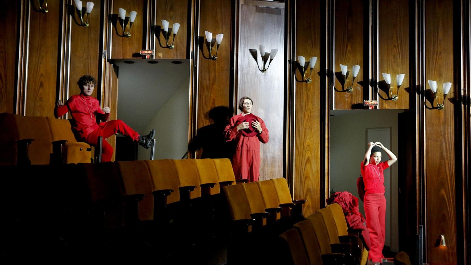 Eine Szene aus "Die Befristeten" am Schauspielhaus Bochum. Die Schauspieler*innen Dominik Dos-Reis, Marius Huth und Gina Haller stehen mit Abstand im leeren Zuschauerraum aufgereiht, in rot angezogen.