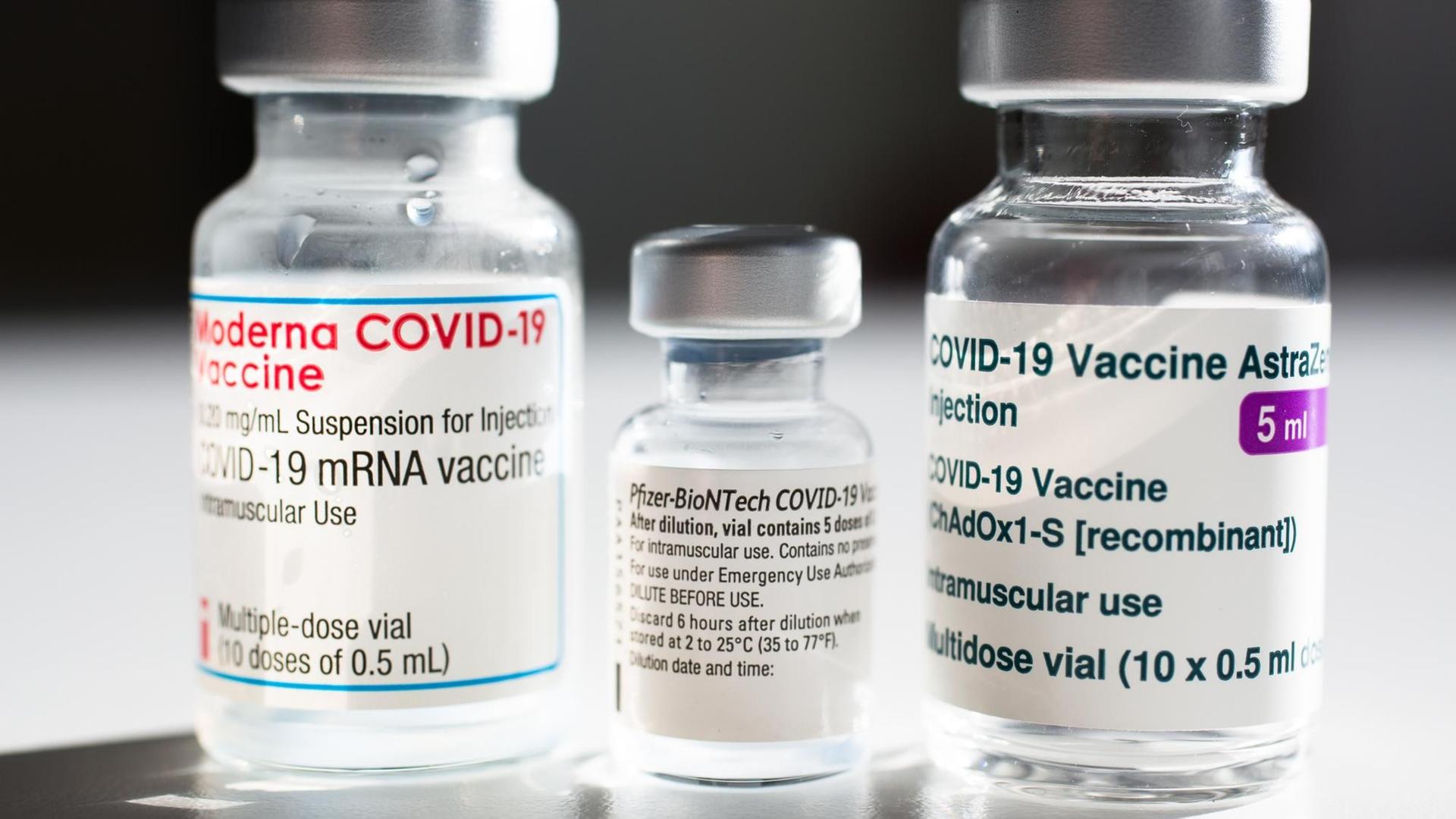 Drei Impfampullen der Hersteller Biontech/Pfizer, Moderna und AstraZeneca stehen nebeneinander