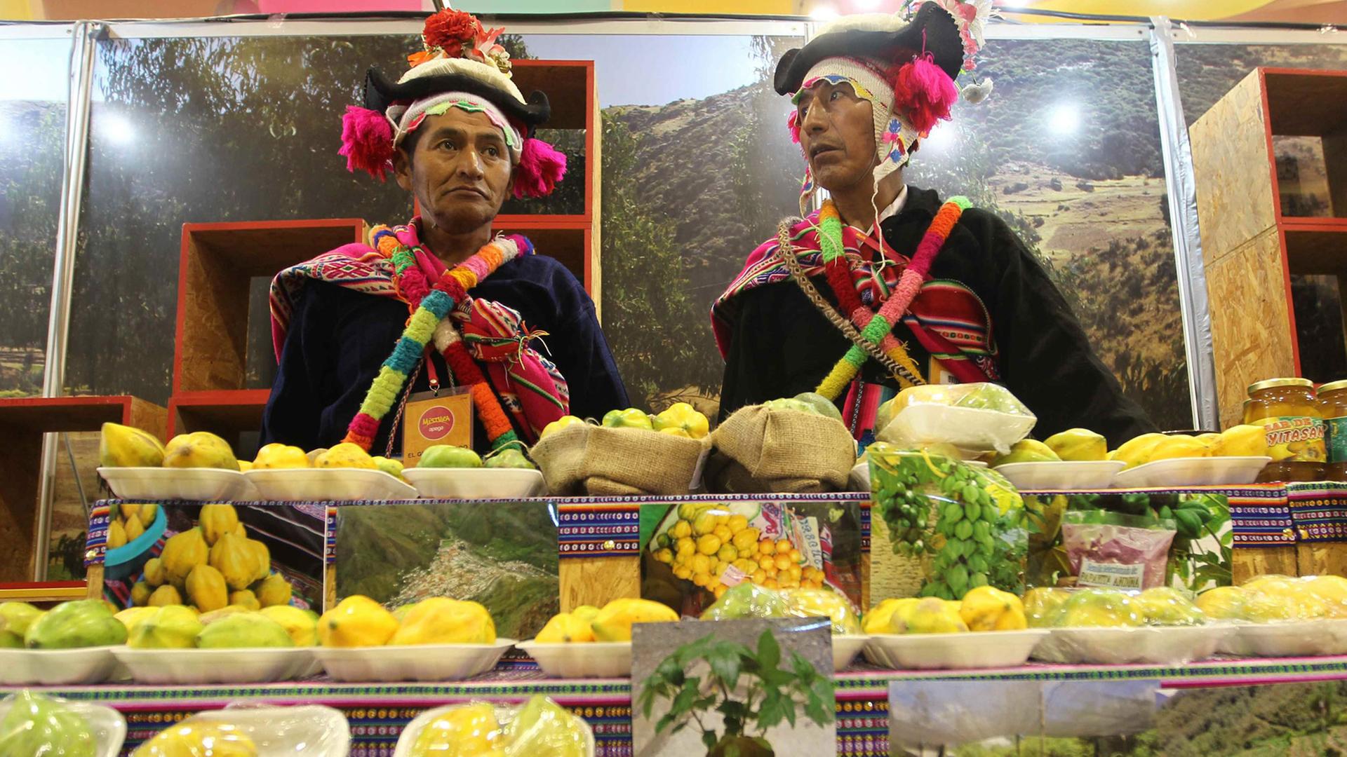 Zwei Männer in peruanischer Tracht hinter der Theke an einem Stand auf einer jährlich stattfindenden Gastronomie-Messe in Lima.