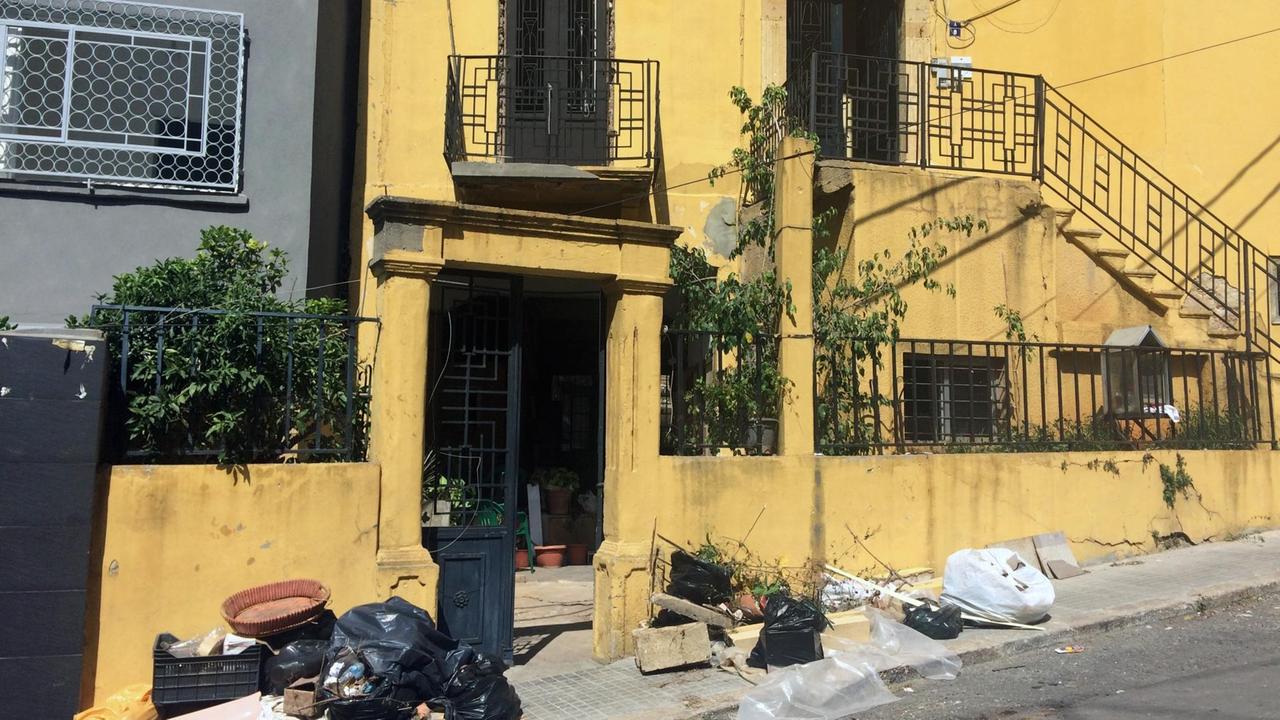 Senfgelbes Haus mit Art Deco in Beirut, davor Zeichen der zerstörerischen Explosion