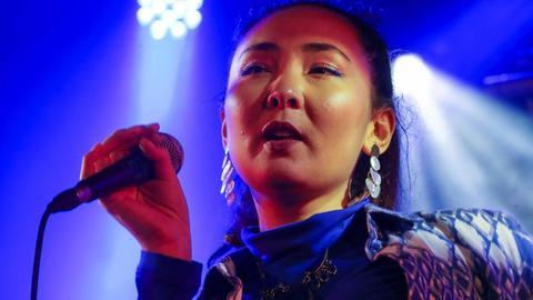 Die afghanische Sängerin Elaha Soroor singt auf einer Bühne in ein Mikrofon.